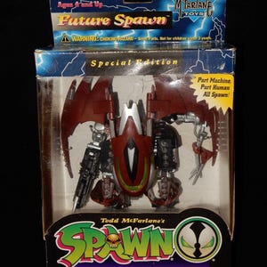 May include: A boxed "Future Spawn" action figure by McFarlane Toys. The figure is red, silver, and black, with articulated wings and mechanical details. The packaging includes the text "Special Edition" and "Ultra-Action Figures".
