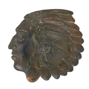 May include: A bronze-colored relief sculpture of a Native American man's profile. The sculpture features a detailed headdress with feathers and a central circular emblem. The artwork is set against a white background.