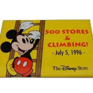 Puede incluir: Pin rectangular amarillo con Mickey Mouse subiendo una escalera. El pin tiene el texto "500 STORES & CLIMBING! - July 5, 1996 - The Disney Store". Mickey Mouse lleva pantalones cortos rojos, zapatos amarillos y guantes blancos.