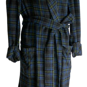 May include: A long, plaid robe in shades of blue, green, and black. The robe has a shawl collar, long sleeves with turned-up cuffs, and a matching belt. It features two front pockets and is made of a soft, woven fabric.