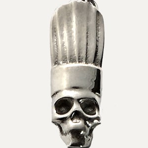 May include: Silver charm in the shape of a chef's hat with a skull underneath.