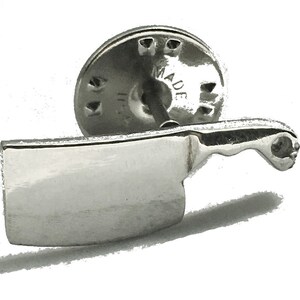 May include: Silver-toned cleaver shaped lapel pin with a round back that says "MADE IN ITALY".