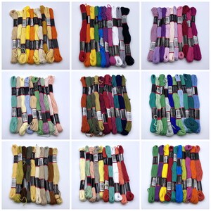 May include: Assortment of embroidery floss spools in various colours, including red, blue, green, yellow, orange, purple, and white. The spools are arranged in rows and are ready for crafting projects.
