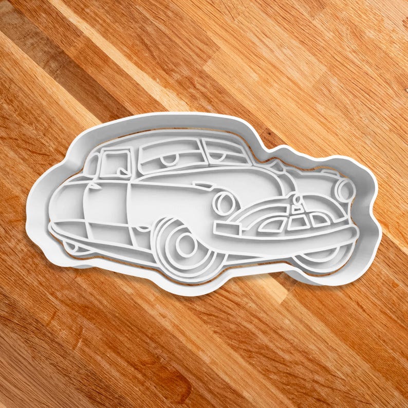 May include: White plastic cookie cutter shaped like a vintage car with a cartoon face.