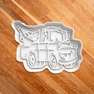 May include: White plastic cookie cutter shaped like a cartoon tow truck with a smiling face.