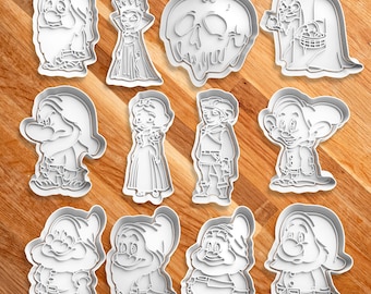 May include: A set of 12 white plastic cookie cutters featuring characters from the fairy tale Snow White and the Seven Dwarfs. The cutters include Snow White, the Evil Queen, the Prince, a poisoned apple, and seven dwarfs.