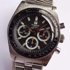 May include: Vintage Tissot PR 516 chronograph watch with a black dial, white sub-dials, and a stainless steel bracelet. The watch features a date display and three sub-dials. The watch case is approximately 40mm in diameter.