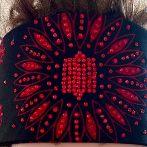 May include: Black bandana with a red rhinestone design of a flower with a circular pattern.