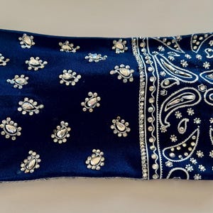 May include: A dark blue bandana headband with a paisley pattern and silver rhinestones.