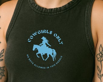 May include: Dark gray tank top with a light blue graphic that reads "Cowgirls Only" with a silhouette of a cowgirl on a horse. The text "No boys allowed in this saddle" is also included in the design.