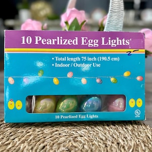 May include: A box of 10 pearlized egg lights, each light is a different pastel color. The box is blue and has a picture of the lights on it. The lights are 75 inches long and can be used indoors or outdoors. The box also has a UL listed label.