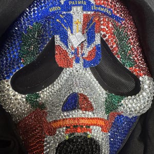 May include: A decorative mask featuring the Dominican Republic flag design, embellished with red, white, blue, and green rhinestones. The mask has the words "DIOS, PATRIA, LIBERTAD" and "REPUBLICA DOMINICANA".