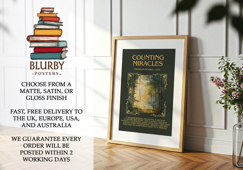 May include: A framed poster with the title "Counting Miracles" by Nicholas Sparks. The poster features a forest scene with a deer. The frame is light brown. The poster is displayed on a wooden surface.
