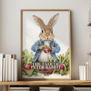 Könnte beinhalten: Ein gerahmter Wandkunstdruck mit einem braunen Kaninchen in einer blauen Jacke, das ein rotes Radieschen hält. Unter dem Kaninchen befinden sich grüne Radieschenblätter und weitere rote Radieschen. Der Text lautet THE TALE OF PETER RABBIT, BEATRIX POTTER, 1902.
