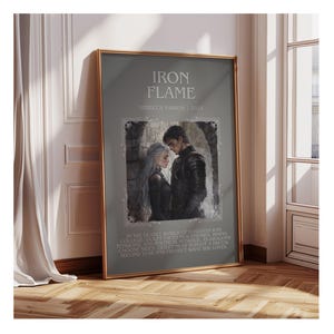 May include: Framed art print titled "Iron Flame" by Rebecca Yarros, 2023. The artwork features a couple in dark attire, set against a stone background. The print includes text describing the story's setting and plot.