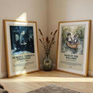 May include: Two framed art prints with wooden frames lean against a wall. One features a dark, moody scene with text "Hercule Poirot's Christmas." The other depicts a frog and a rat in a boat, with text "Wind in the Willows."