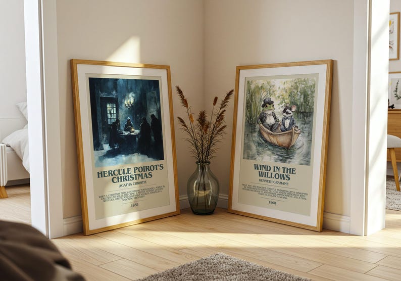 May include: Two framed art prints with wooden frames lean against a wall. One features a dark, moody scene with text "Hercule Poirot's Christmas." The other depicts a frog and a rat in a boat, with text "Wind in the Willows."