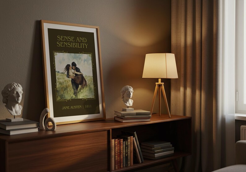 May include: A framed print of "Sense and Sensibility" by Jane Austen, displayed on a wooden cabinet. The print features a romantic illustration. A lamp with a beige shade and a bust sculpture are also on the cabinet.