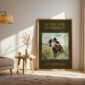 May include: A framed print of "Sense and Sensibility" by Jane Austen. The artwork features a couple embracing in a field, with the title and author's name in gold lettering. The frame is a light wood color, and the print is displayed in a well-lit room.