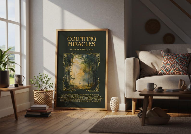 May include: A framed poster with the title "COUNTING MIRACLES" by Nicholas Sparks. The poster features a forest scene with a deer. The text is in gold on a dark green background. The poster is displayed in a living room setting.