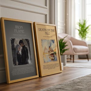 May include: Two framed art prints with wooden frames. The left print is titled "IRON FLAME" with an illustration of a couple. The right print is titled "DEATH ON THE NILE" with a watercolor painting of a ship. Both prints are leaning against a wall.