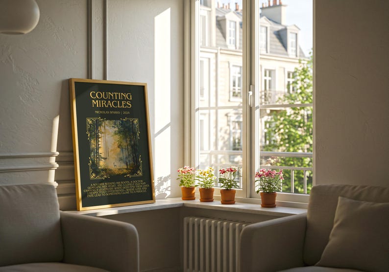 May include: A framed art print titled "Counting Miracles" with a forest scene, displayed near a window with potted flowers. The print has a gold frame and is set against a neutral-toned wall. Two armchairs are in the foreground.