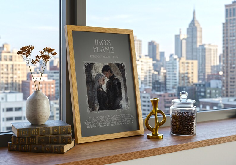 May include: A framed print with the text "IRON FLAME" and an illustration of a couple. The print is displayed on a wooden surface with books, a vase with dried flowers, a gold-colored sculpture, and a glass jar filled with coffee beans. The background shows a cityscape.