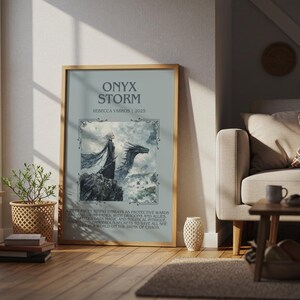 May include: A framed art print titled "ONYX STORM" by Rebecca Yarros, 2015, featuring a fantasy illustration of a figure with a dragon. The artwork is displayed in a living room setting with a window, plants, and a sofa.