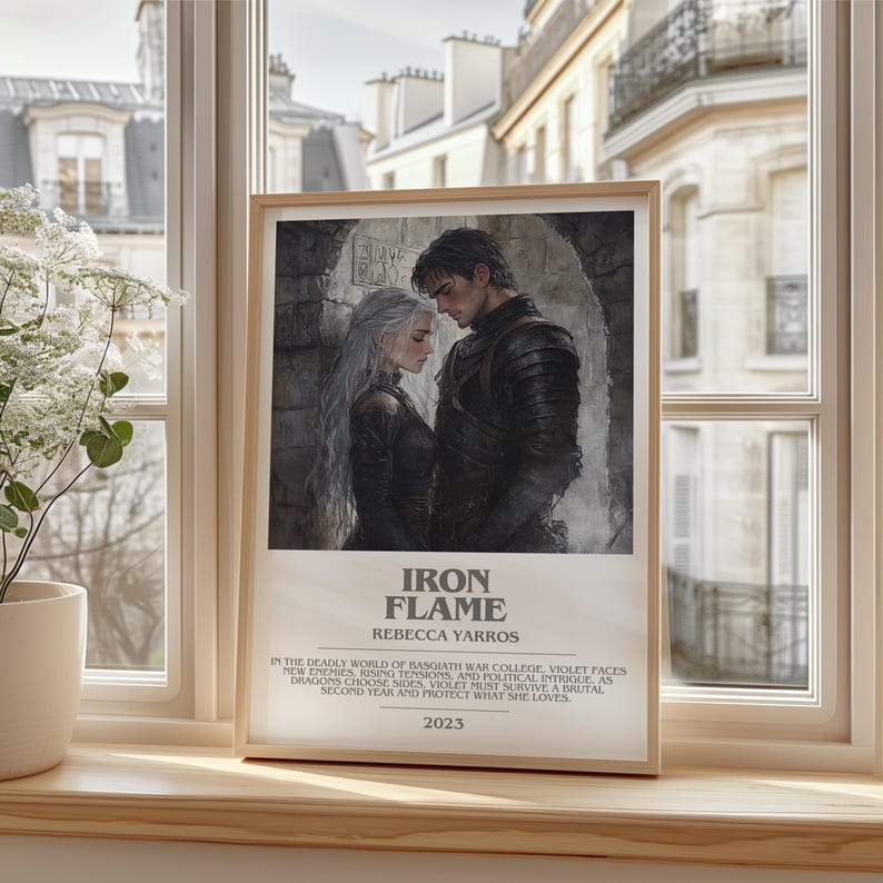 May include: A framed print featuring a romantic illustration of a couple in a medieval setting. The artwork is in muted tones, with the title "IRON FLAME" and author's name, "REBECCA YARROS," displayed below. The print includes text describing the story and the year 2023.