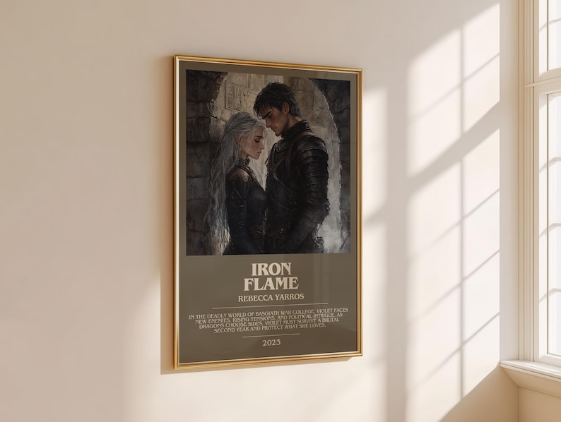 May include: A framed poster with a gold border hangs on a beige wall. The poster features a grayscale illustration of two people in a romantic embrace. The text "IRON FLAME" and "REBECCA YARROS" are visible, along with additional text and the year "2023".