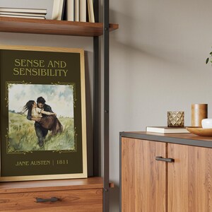 May include: A framed print of "Sense and Sensibility" by Jane Austen. The artwork depicts a couple embracing in a field, with the title and author's name in elegant lettering. The frame is a light wood color.