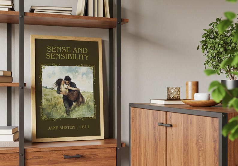 May include: A framed print of "Sense and Sensibility" by Jane Austen. The artwork depicts a couple embracing in a field, with the title and author's name in elegant lettering. The frame is a light wood color.