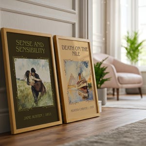 May include: Two framed book covers, "Sense and Sensibility" and "Death on the Nile", lean against a wall. The first features a couple in a field, the second a ship. Both are in wooden frames.