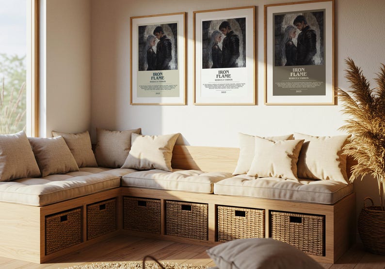May include: A cozy corner seating area with a wooden frame, beige cushions, and woven storage baskets. Three framed posters with the text "IRON FLAME" hang above the seating. The room is bathed in natural light.