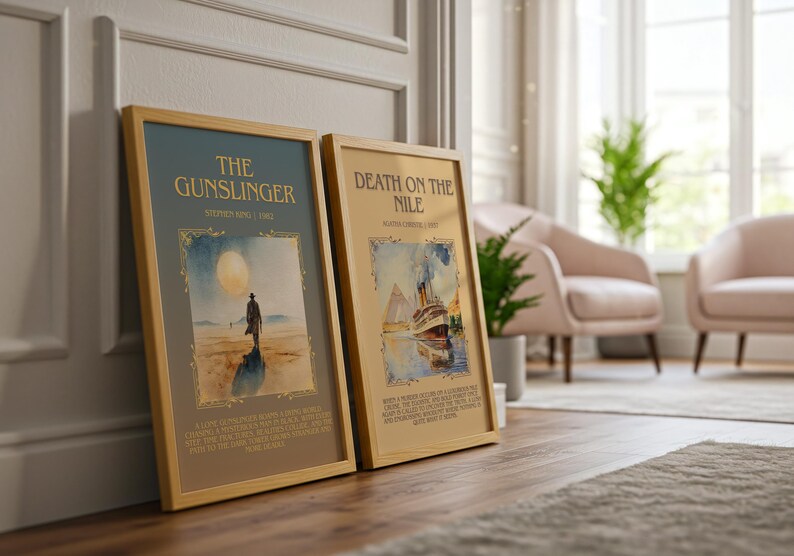 May include: Two framed book covers, "The Gunslinger" and "Death on the Nile", are propped against a wall. "The Gunslinger" shows a lone figure under a large moon. "Death on the Nile" depicts a ship. Both are in wooden frames.
