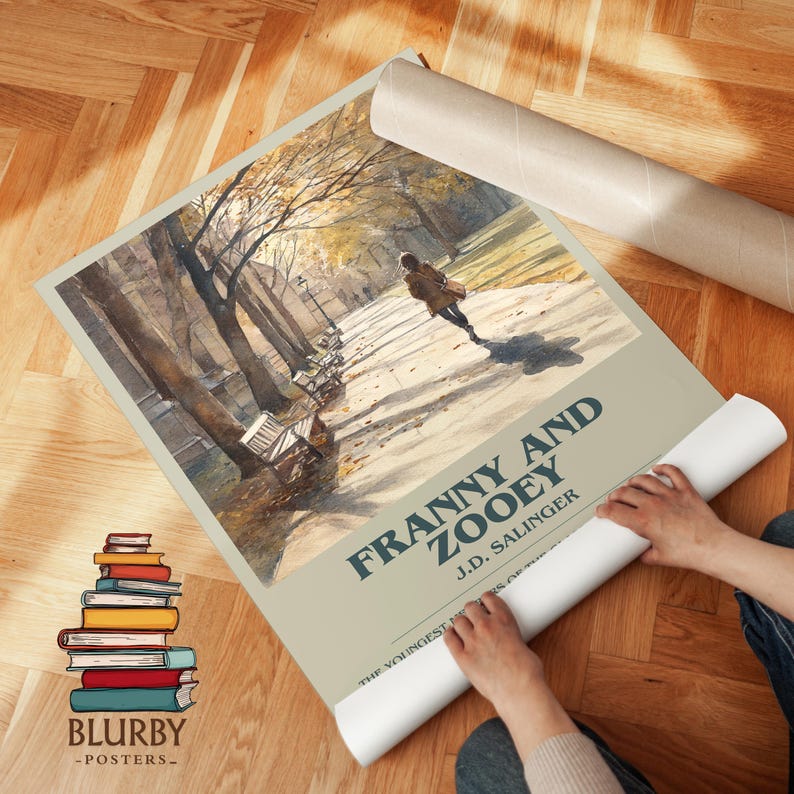 K&ouml;nnte beinhalten: Ein Poster mit dem Titel "Franny and Zooey" von J.D. Salinger, das eine Aquarellillustration einer Person zeigt, die auf einem Weg in einem Park geht. Das Poster ist teilweise aufgerollt, mit dem Titel in dunkler blauer Schrift. Ein Stapel B&uuml;cher ist sichtbar.