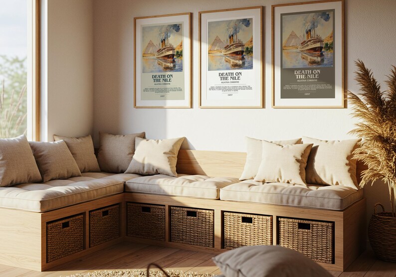 May include: Three framed posters of a vintage film advertisement, "Death on the Nile," hang above a built-in bench with beige cushions and pillows. Woven baskets are stored below the bench, and a tall plant is in a basket.