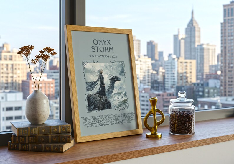 May include: A framed print titled "Onyx Storm" with a fantasy illustration of a person and a dragon. Beside it are stacked books, a vase with dried flowers, a gold sculpture, and a glass jar filled with coffee beans. The scene is set by a window with a city view.