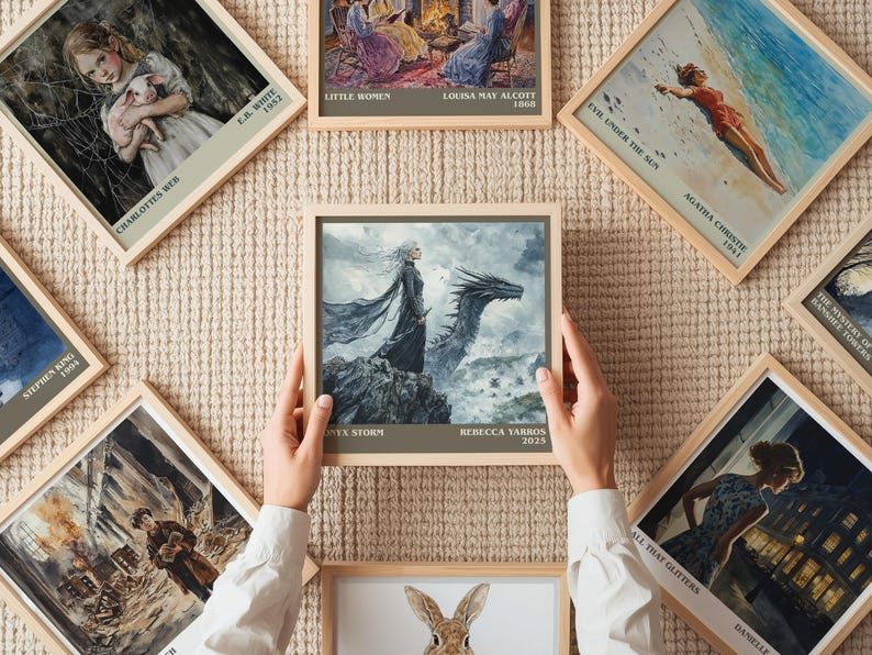 May include: A collection of framed art prints featuring book covers and illustrations. One print shows a woman with a dragon, with the text "TX-STORM" and "REBECCA YARROS 2023". Other prints include "CHARLOTTES WEB", "LITTLE WOMEN", and "EVIL UNDER THE SUN".