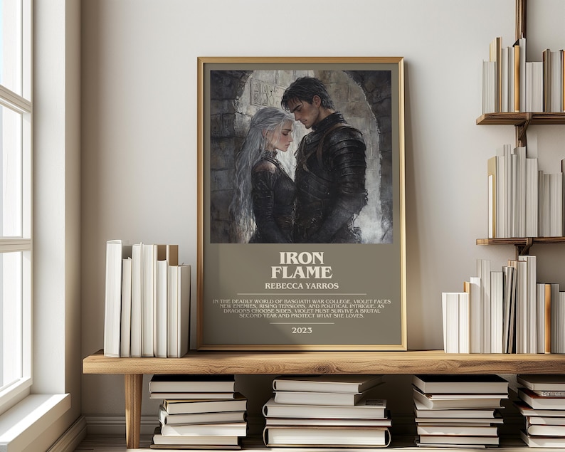 May include: A framed print of "Iron Flame" by Rebecca Yarros, featuring a couple in medieval attire. The print has a gold frame and is displayed on a wooden shelf with books. The text "Iron Flame" and the author's name are visible.