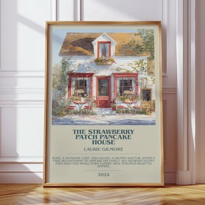 Könnte beinhalten: Ein gerahmter Druck von "The Strawberry Patch Pancake House" mit einer Aquarellillustration eines charmanten Cafés. Der Druck enthält Text mit dem Namen des Autors, einer kurzen Zusammenfassung der Handlung und dem Jahr 2024.
