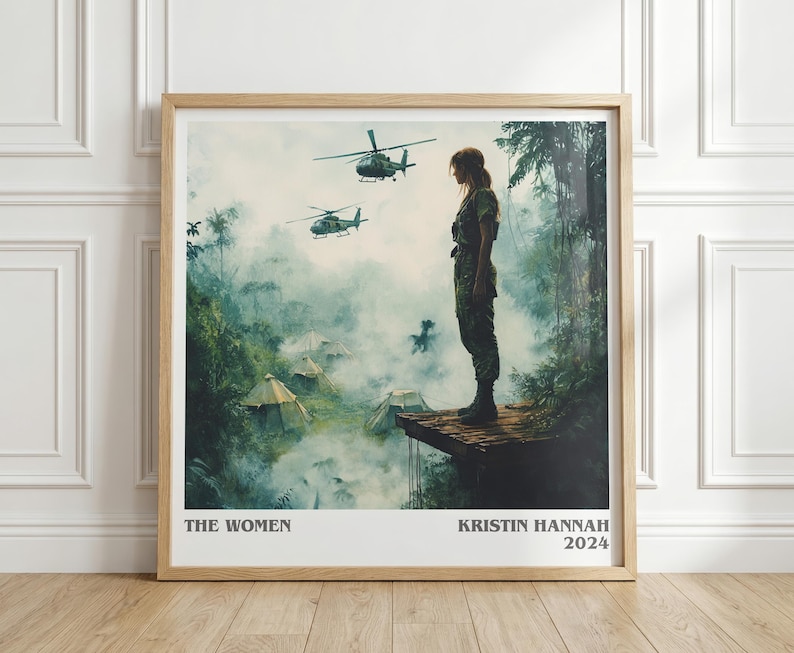 May include: Framed print featuring a woman in military attire standing on a wooden platform, with helicopters flying overhead. The artwork has a jungle backdrop with tents and smoke. Text at the bottom reads "THE WOMEN" and "KRISTIN HANNAH 2024".