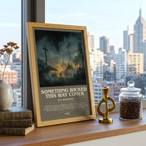 May include: A framed print of "Something Wicked This Way Comes" by Ray Bradbury. The artwork depicts a carnival scene with a dark, ominous atmosphere. The print is displayed on a wooden surface with books, a vase, and a glass jar filled with coffee beans.