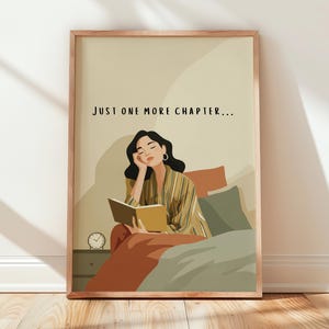 May include: A framed art print depicting a person reading in bed, with the text "JUST ONE MORE CHAPTER...". The illustration shows a person in a striped shirt holding a book. The color scheme includes beige, brown, and green tones.
