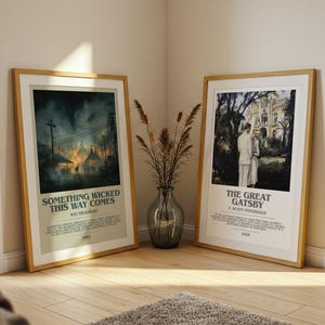May include: Two framed movie posters, leaning against a wall. One features the text "SOMETHING WICKED THIS WAY COMES" and the other "THE GREAT GATSBY". Both posters are in wooden frames and have a cream-colored border.