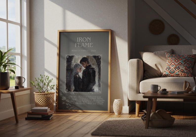 May include: A framed print with the text "IRON FLAME" and an illustration of a couple. The print is in a wooden frame and is displayed in a living room setting. The room has a sofa, coffee table, and a window.