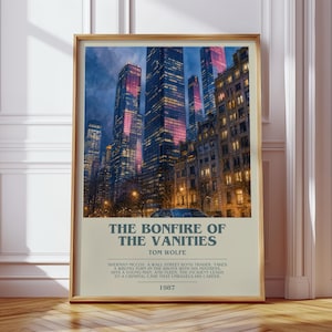 May include: A framed vertical poster featuring a night cityscape of skyscrapers with illuminated windows. Below the image, the text reads: THE BONFIRE OF THE VANITIES, TOM WOLFE, and a summary of the book plot, followed by the year 1987.