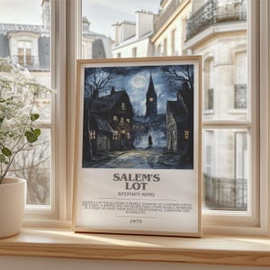 May include: Framed print of a dark, atmospheric illustration depicting a town at night under a full moon. The artwork features a church steeple and the text "SALEM'S LOT" by Stephen King, with the year 1975.