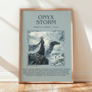 May include: Framed art print titled "Onyx Storm" by Rebecca Yarros, 2025. The artwork features a woman in a flowing black gown standing on a rocky outcrop with a dragon. The background is a light blue with text describing the story.