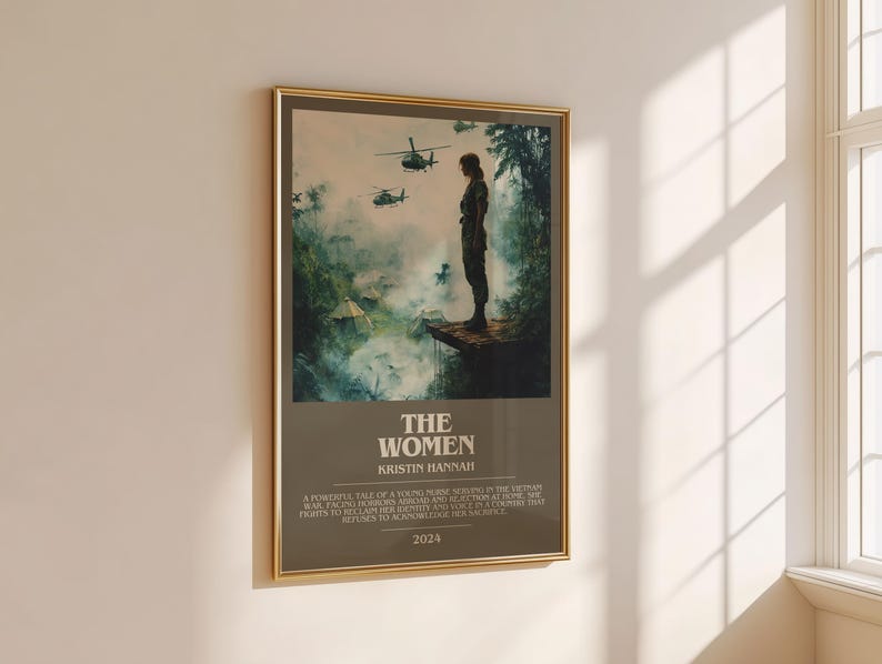 Puede incluir: Un p&oacute;ster enmarcado con borde dorado, que muestra a una mujer de pie en una plataforma con helic&oacute;pteros al fondo. El p&oacute;ster tiene el t&iacute;tulo "THE WOMEN", el nombre de la autora, Kristin Hannah, texto y el a&ntilde;o 2024.